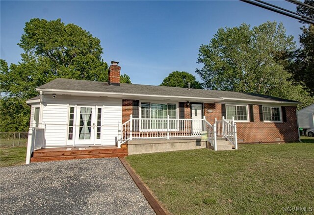 ranch-style home featuring covered porch, a chimney, a front lawn, and brick siding