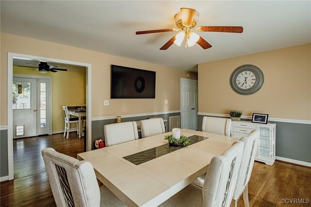 dining space with baseboards, a ceiling fan, and dark wood-type flooring