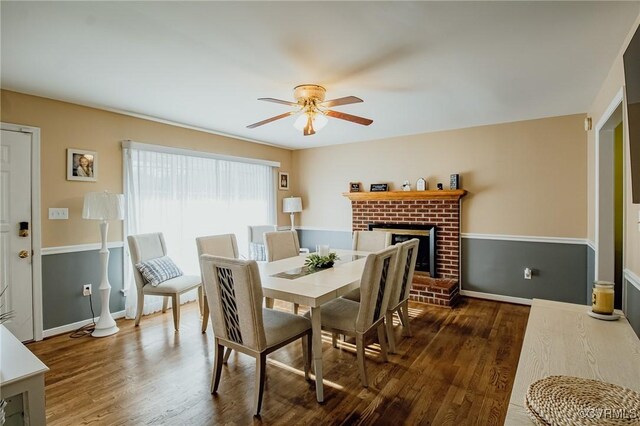 dining space with baseboards, ceiling fan, a fireplace, and wood finished floors