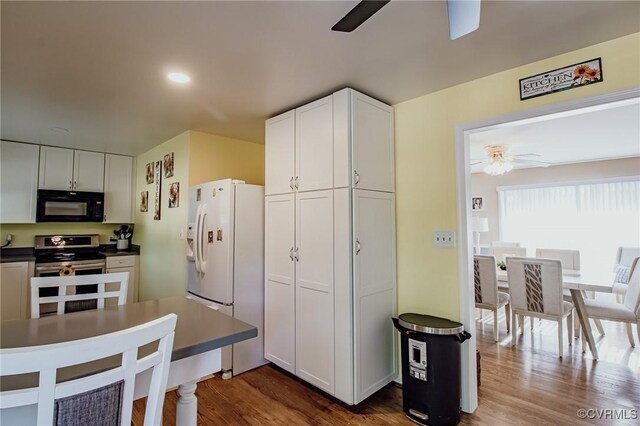 kitchen with a ceiling fan, black microwave, white refrigerator with ice dispenser, dark wood-style floors, and stainless steel electric stove