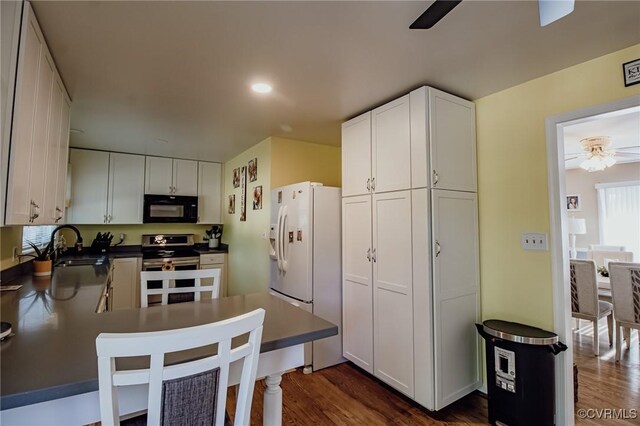 kitchen featuring a ceiling fan, electric range, black microwave, a sink, and white fridge with ice dispenser