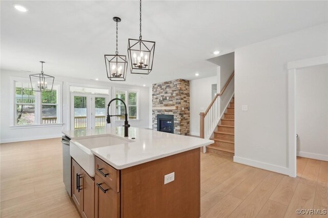 kitchen with light countertops, open floor plan, a notable chandelier, and a stone fireplace