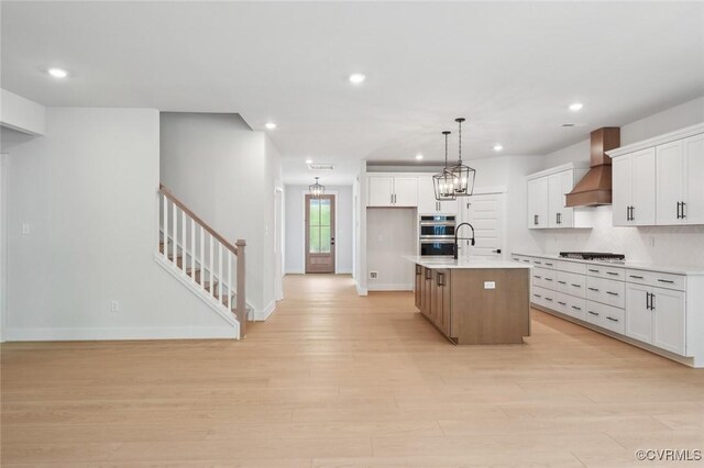 kitchen with wall chimney range hood, baseboards, recessed lighting, and light wood-style flooring