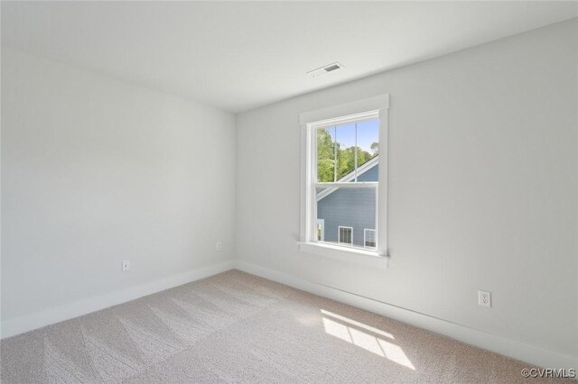 carpeted empty room featuring baseboards and visible vents