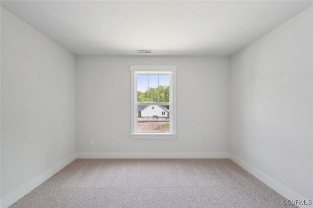 spare room with light colored carpet, baseboards, and visible vents