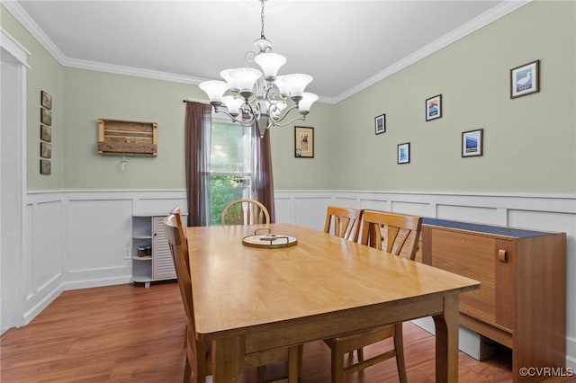 dining area with a decorative wall, wood finished floors, and a chandelier