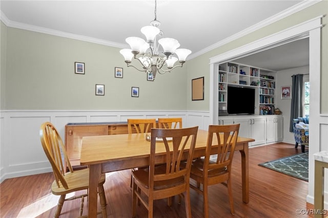 dining space featuring crown molding, a notable chandelier, and wood finished floors