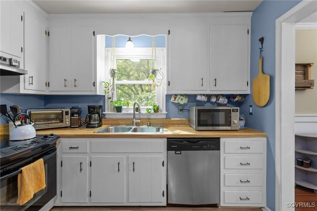 kitchen featuring a toaster, light countertops, ventilation hood, a sink, and appliances with stainless steel finishes