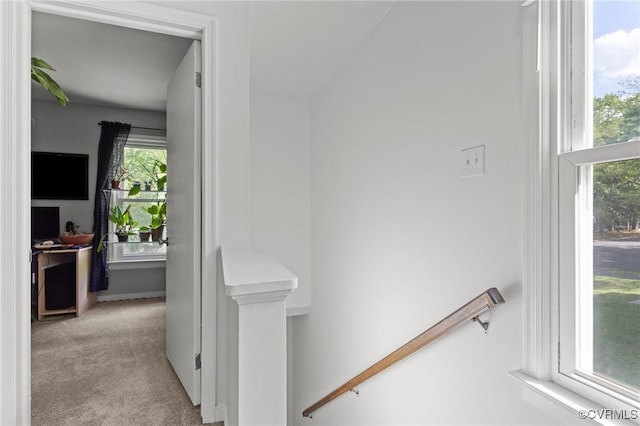 hallway with baseboards, carpet, and an upstairs landing