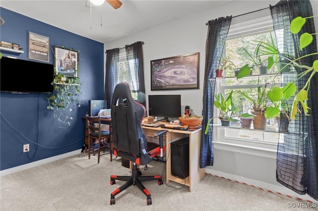 carpeted office space with a ceiling fan and baseboards