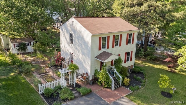 view of front facade with stairway, fence, a shingled roof, and a front lawn