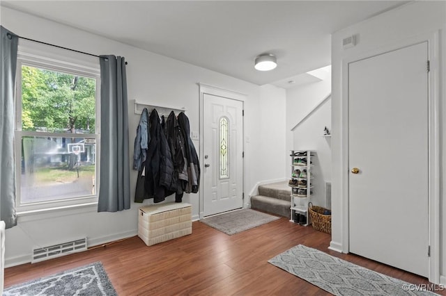 foyer with stairs, visible vents, and wood finished floors