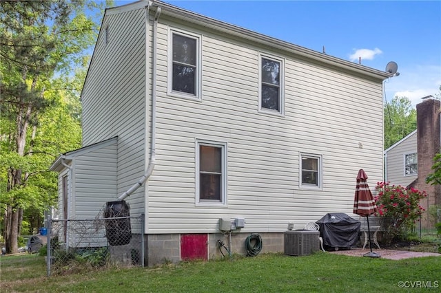 back of house with central air condition unit, fence, and a yard
