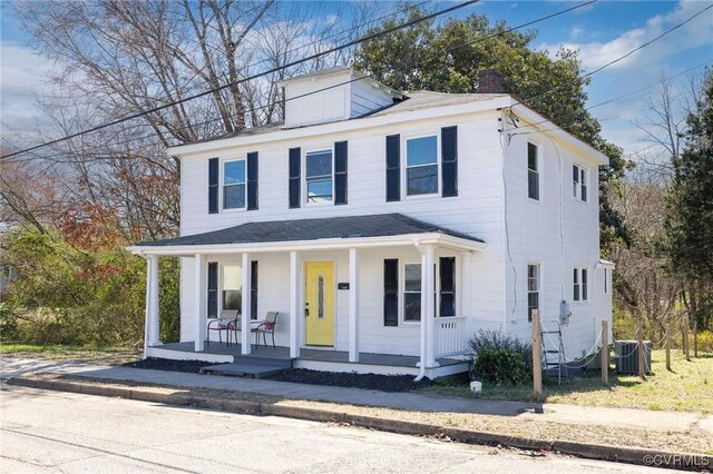 traditional style home with covered porch, central AC, and a chimney