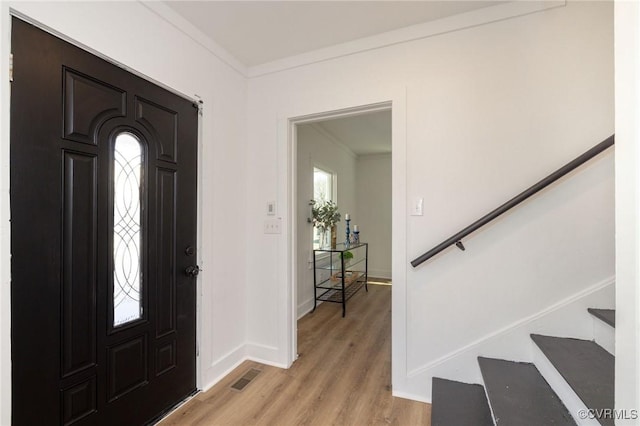 foyer featuring visible vents, crown molding, baseboards, stairway, and light wood finished floors