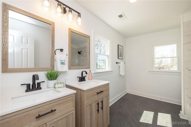 full bath with two vanities, plenty of natural light, and a sink