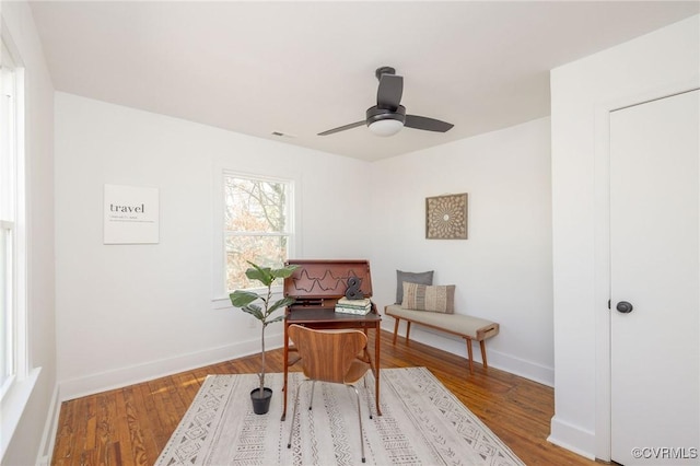 living area featuring baseboards, ceiling fan, and wood finished floors