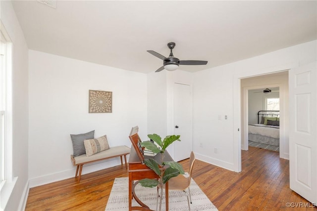living area with baseboards, ceiling fan, and hardwood / wood-style floors