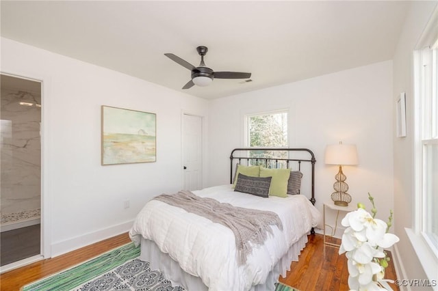 bedroom featuring a ceiling fan, visible vents, wood finished floors, baseboards, and ensuite bathroom