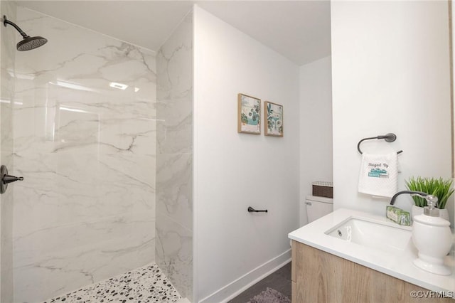 full bath featuring baseboards, a marble finish shower, and vanity