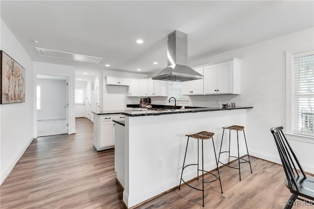 1217 Darbytown Rd, Richmond, VA 23231 - kitchen with a peninsula, a breakfast bar, island range hood, white cabinetry, and a wealth of natural light
