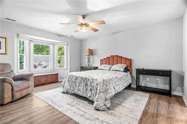 bedroom featuring baseboards, a ceiling fan, wood finished floors, and visible vents