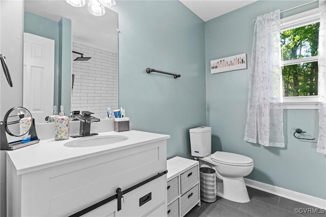 bathroom with vanity, toilet, tile patterned floors, baseboards, and tiled shower