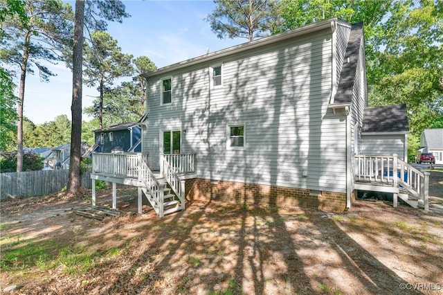 rear view of property with a sunroom, stairway, fence, and a deck