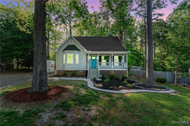 bungalow-style house with roof with shingles, fence, covered porch, and a front yard