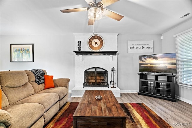 living area with visible vents, wood finished floors, a fireplace, baseboards, and a ceiling fan
