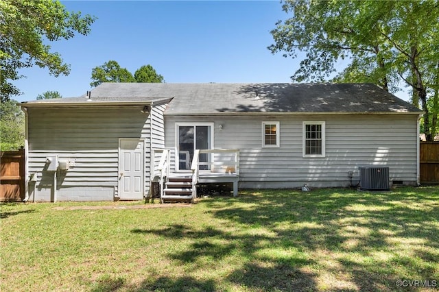 rear view of house with fence, a wooden deck, a yard, and central AC