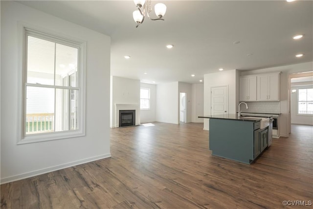 6081 Brickshire Dr, Providence Forge, VA 23140 - kitchen featuring dark countertops, a fireplace, dark wood finished floors, a notable chandelier, and an island with sink