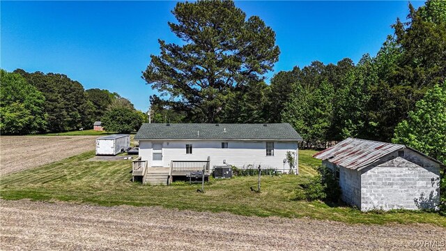 back of house with a storage shed, a lawn, a wooden deck, and an outbuilding