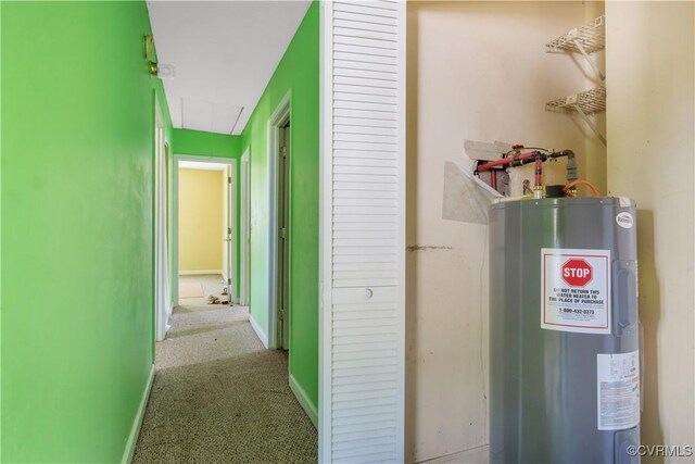hallway with attic access, baseboards, carpet, and water heater