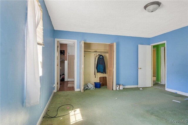 unfurnished bedroom with baseboards, carpet flooring, and a closet
