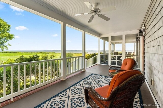 sunroom / solarium featuring a ceiling fan and a water view