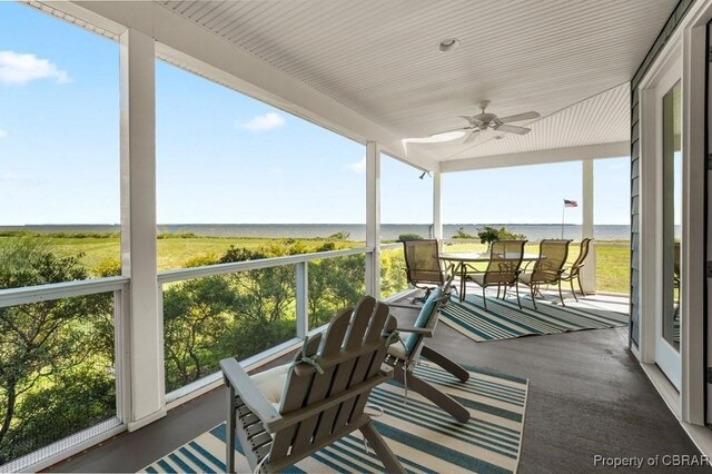 sunroom / solarium featuring a ceiling fan and a water view