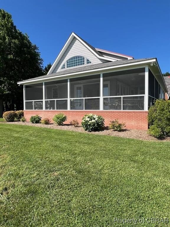 view of front of home featuring brick siding, a front yard, and a sunroom