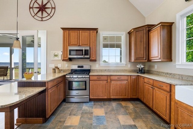kitchen featuring a peninsula, stainless steel appliances, brown cabinets, and a wealth of natural light