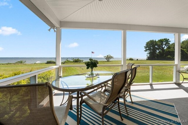 sunroom with a water view and outdoor dining space
