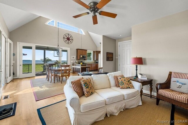 living area featuring a ceiling fan, baseboards, a wealth of natural light, and light wood-type flooring