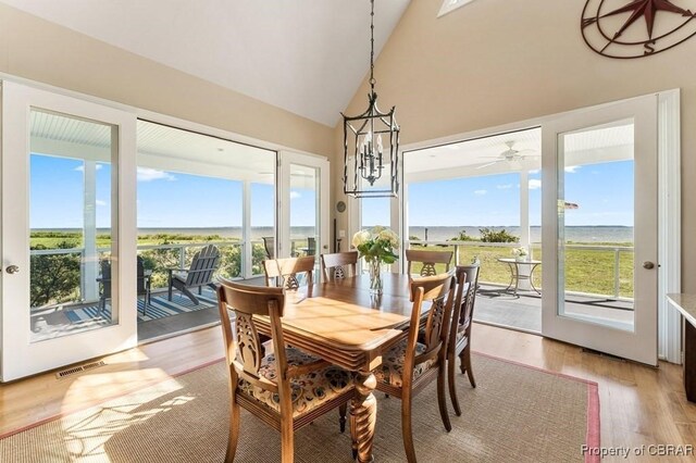 dining area featuring high vaulted ceiling, a notable chandelier, light wood-type flooring, and visible vents