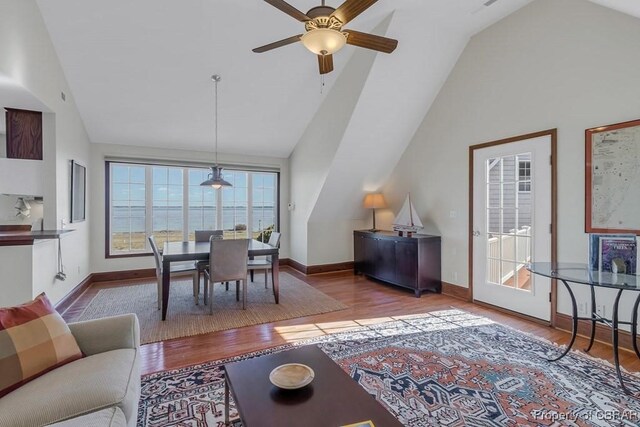 living room with ceiling fan, vaulted ceiling, and wood finished floors