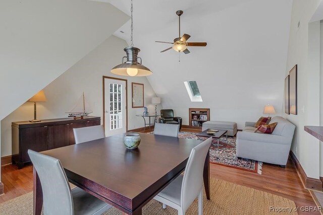 dining space featuring a skylight, baseboards, a ceiling fan, and light wood finished floors
