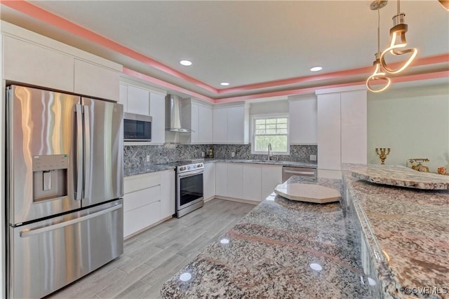 343 Liberty Rd, Buckingham, VA 23123 - kitchen featuring stainless steel appliances, wall chimney exhaust hood, a sink, white cabinetry, and decorative light fixtures