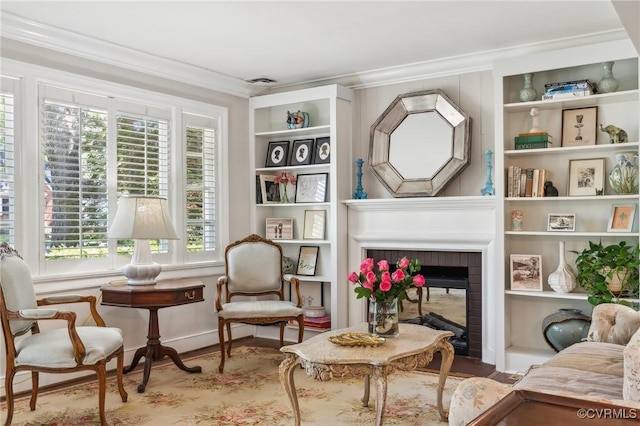 living area featuring ornamental molding, a brick fireplace, built in features, and wood finished floors