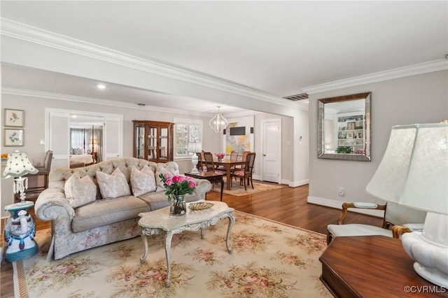 living room featuring wood finished floors, visible vents, crown molding, an inviting chandelier, and baseboards