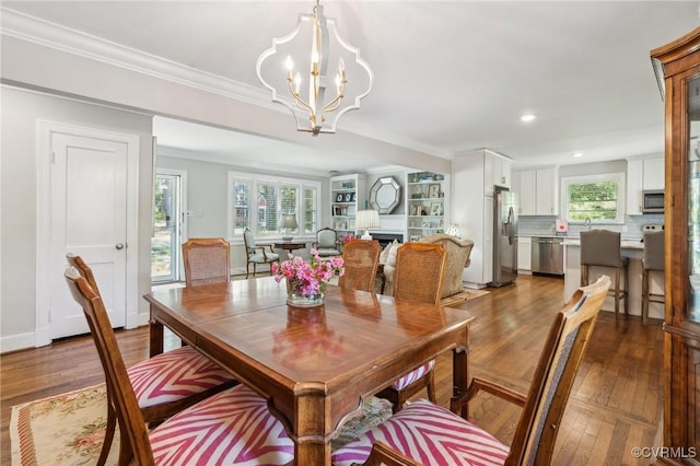 dining area featuring an inviting chandelier, wood finished floors, ornamental molding, and recessed lighting