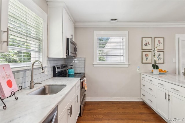 kitchen featuring a sink, stainless steel appliances, visible vents, crown molding, and decorative backsplash