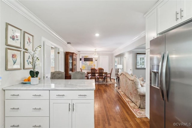 kitchen featuring stainless steel fridge, crown molding, white cabinetry, dark wood-type flooring, and light stone countertops